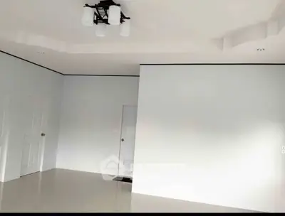 Spacious minimalist room with modern ceiling light fixture and sleek white doors.