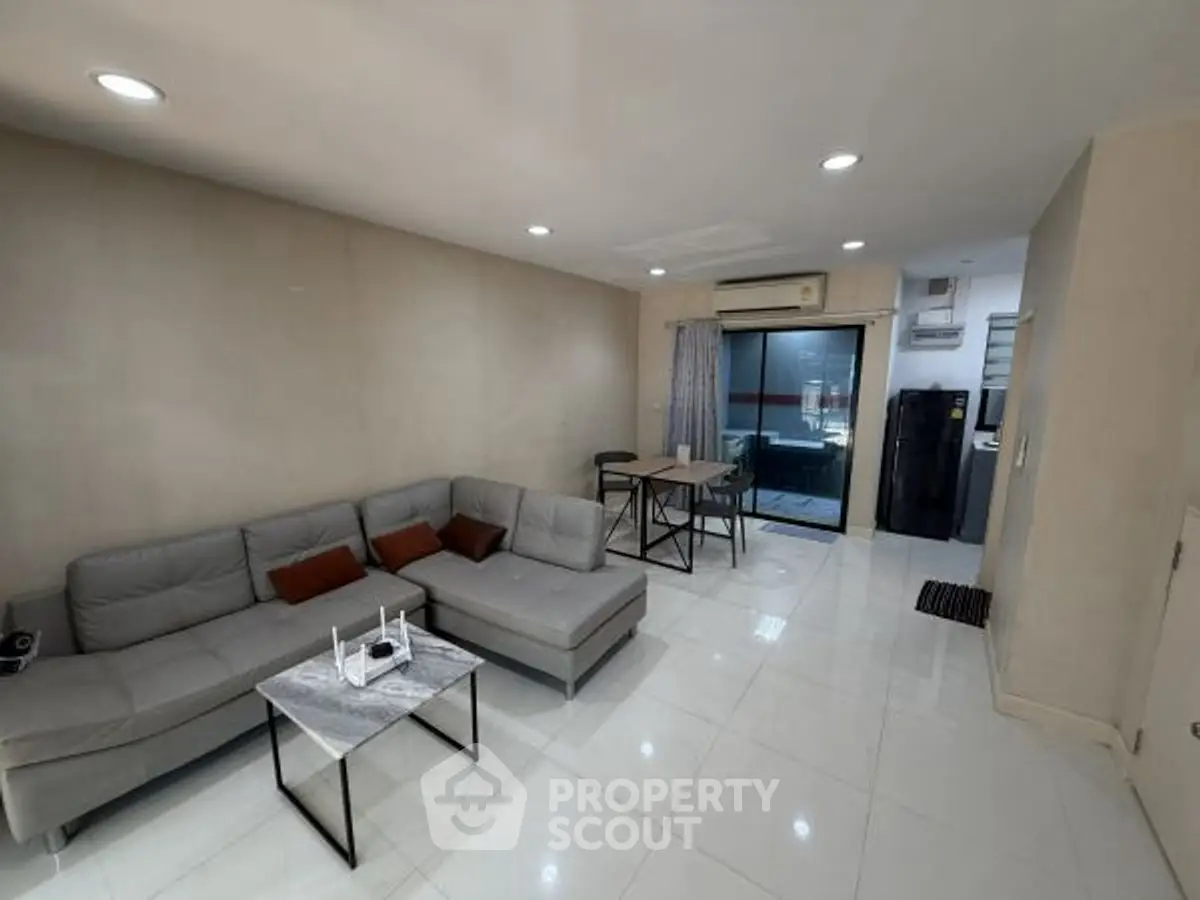 Modern living room with sleek furniture and open layout, featuring a cozy sectional sofa and dining area.