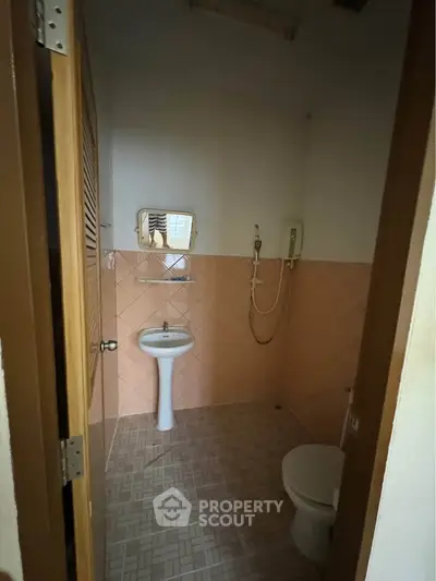 Cozy bathroom with pedestal sink and shower in a compact layout, perfect for efficient living.