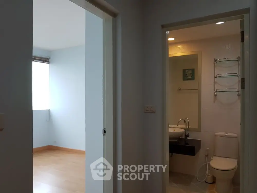 Modern apartment interior with bathroom and adjacent room, showcasing sleek design and natural lighting.