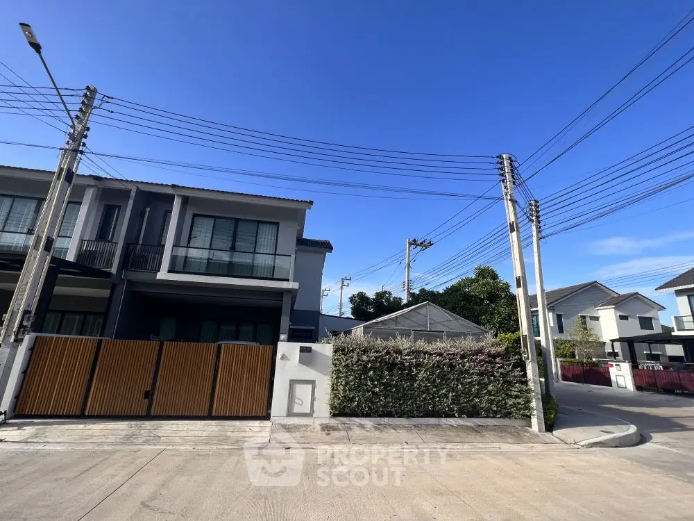 Modern two-story house with gated entrance and clear blue sky