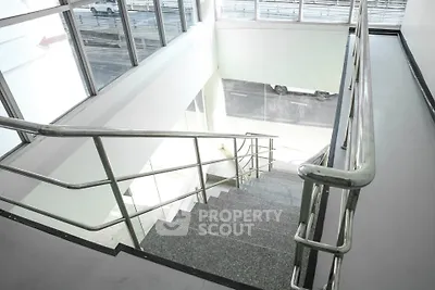 Modern staircase with sleek metal railings and large windows for natural light.