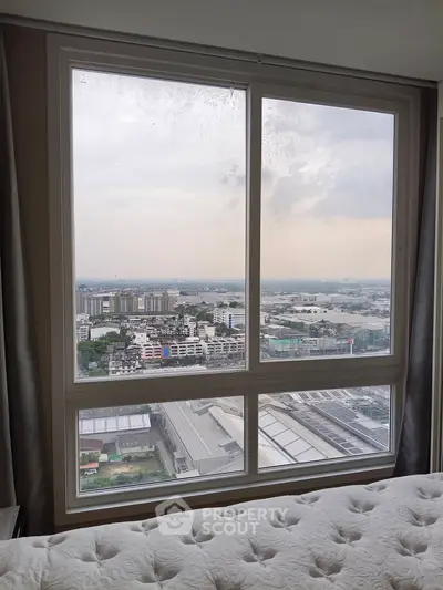 Stunning cityscape view from a high-rise bedroom window, showcasing urban living at its finest.