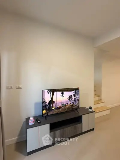 Modern living room with sleek TV stand and staircase, perfect for contemporary living.