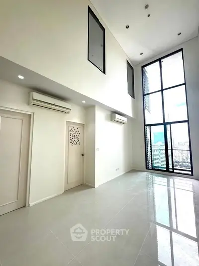 Spacious modern living room with high ceilings and large windows offering city views.