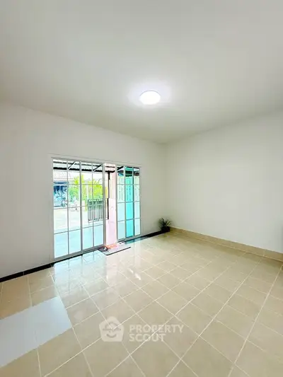 Spacious empty room with large sliding glass doors and tiled floor, perfect for customization.