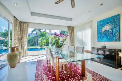 Luxurious dining room with glass table, pool view, and elegant decor