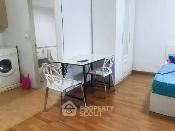 Cozy bedroom with dining area and washing machine, perfect for compact living.