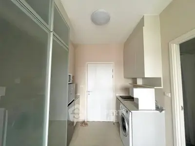 Modern kitchen with sleek appliances and washing machine in compact layout.