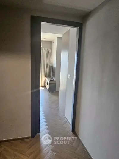 Modern hallway leading to a cozy living area with natural light and stylish flooring.