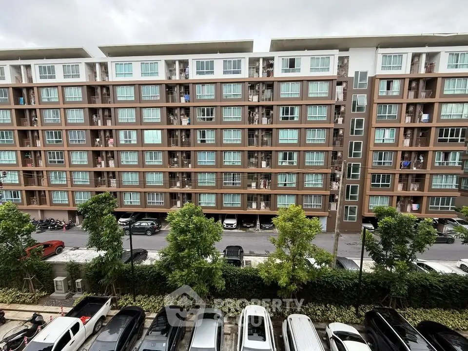 Modern apartment building with multiple floors and parking area, showcasing urban living.