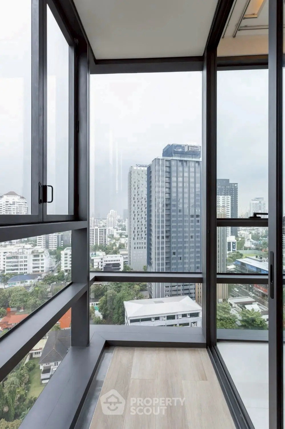 Stunning cityscape view from modern high-rise balcony with floor-to-ceiling windows.