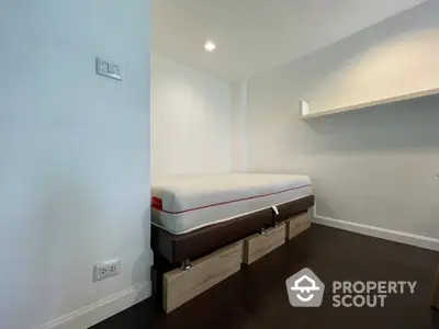 Minimalist bedroom with a single bed and built-in shelving, featuring clean lines and a neutral color palette for a serene living space.