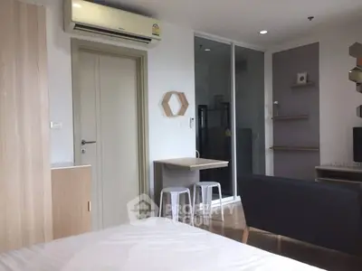 Modern studio apartment with stylish decor and air conditioning, featuring a cozy living area and compact dining space.