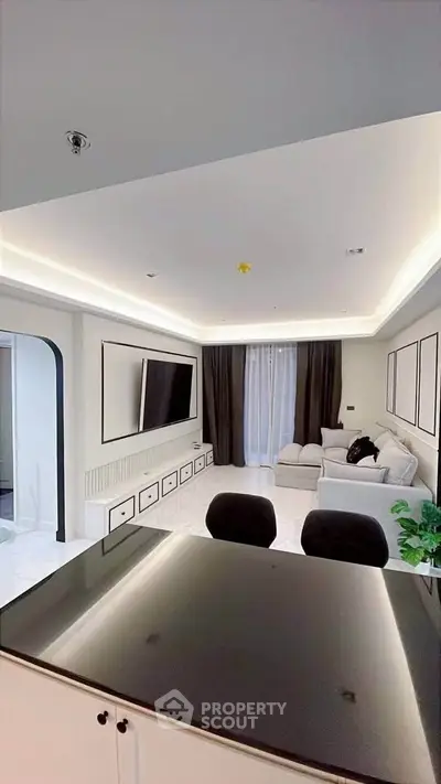 Modern living room with sleek design, featuring a large TV, elegant lighting, and comfortable seating.