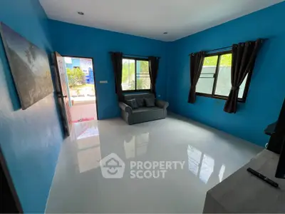 Spacious living room with blue walls and large windows, offering abundant natural light and modern decor.