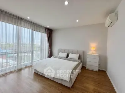 Spacious bedroom with large windows and modern decor in a bright apartment.