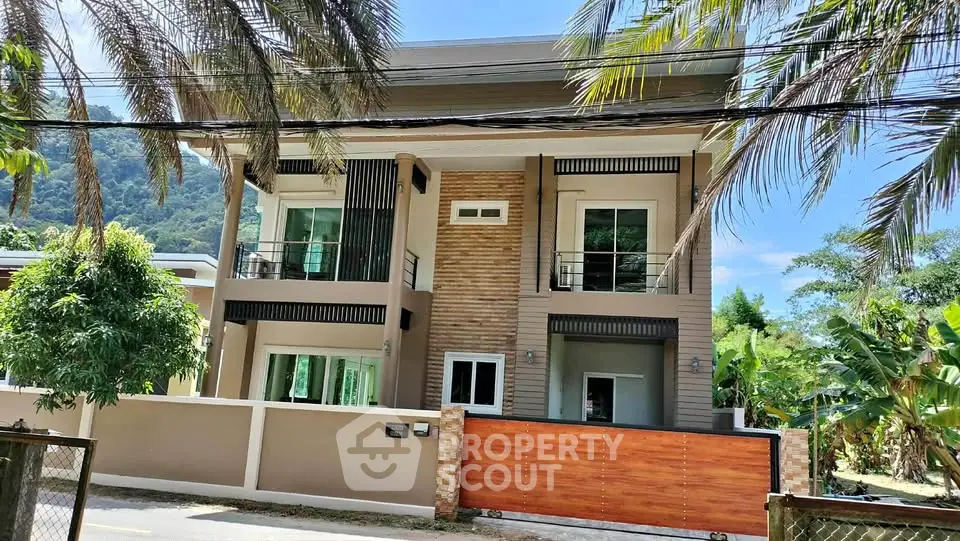 Modern two-story house with large windows and tropical landscaping