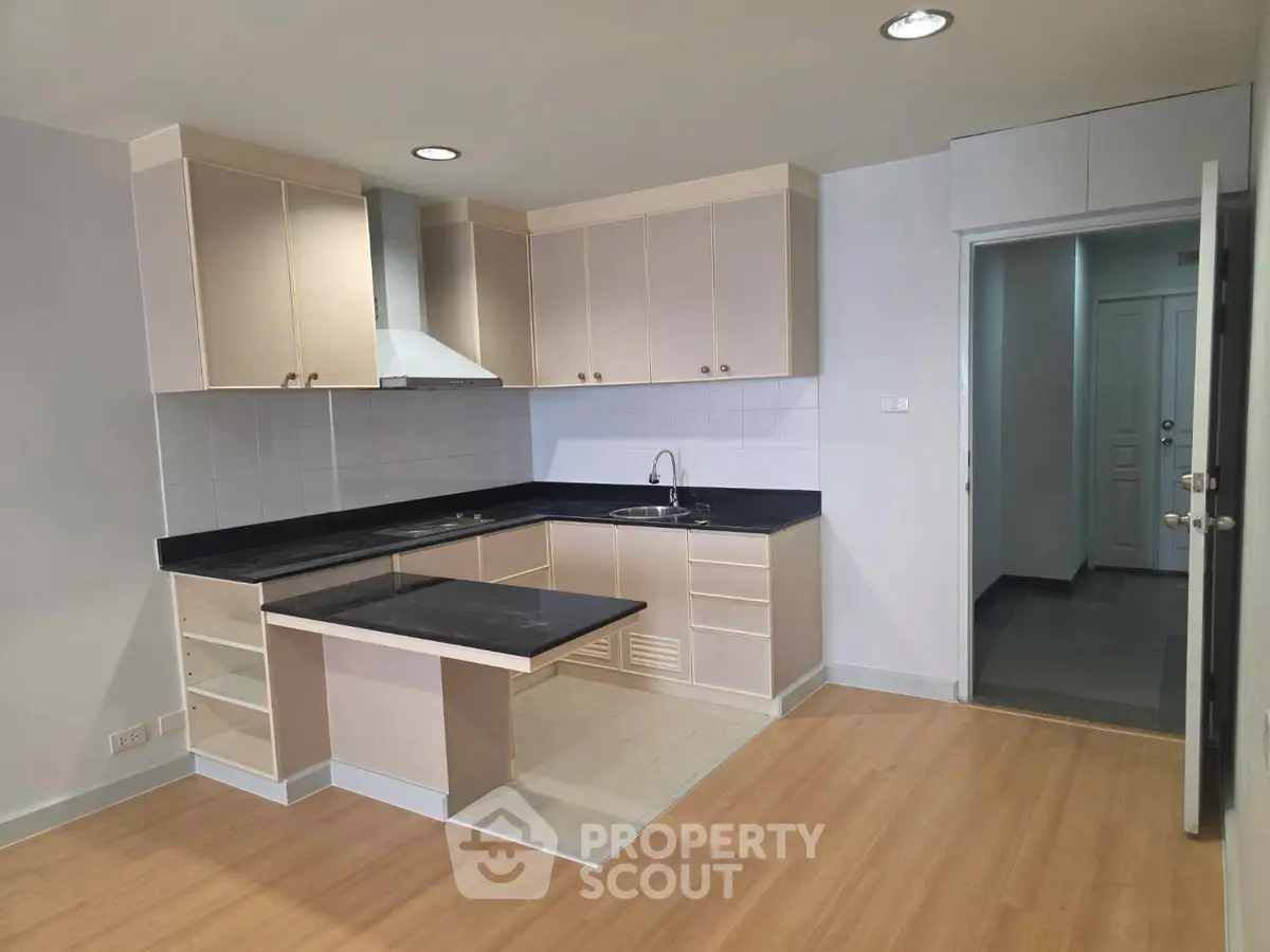 Modern kitchen with sleek cabinetry and black countertops in a spacious apartment.