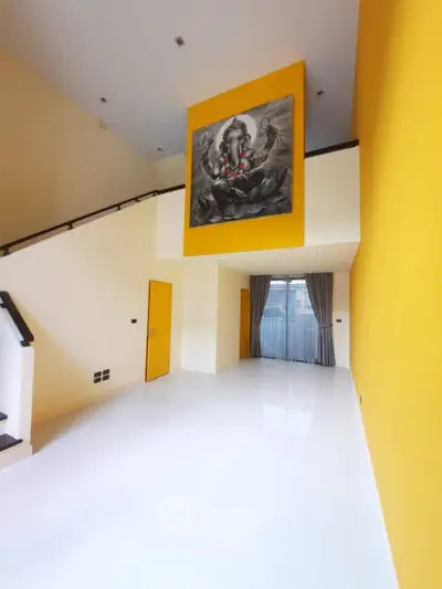Spacious modern living room with high ceiling and vibrant yellow accent wall