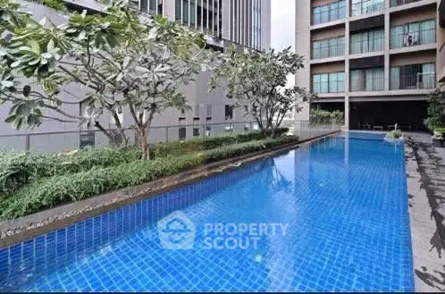 Luxurious apartment complex with a pristine swimming pool and lush greenery.