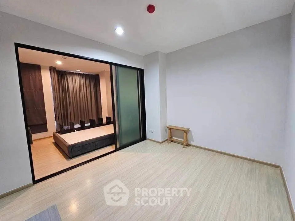 Spacious modern living room with sliding doors leading to a cozy bedroom, featuring sleek wooden flooring.