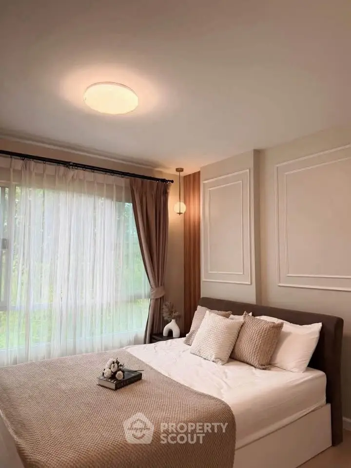 Cozy bedroom with elegant decor and large window offering natural light