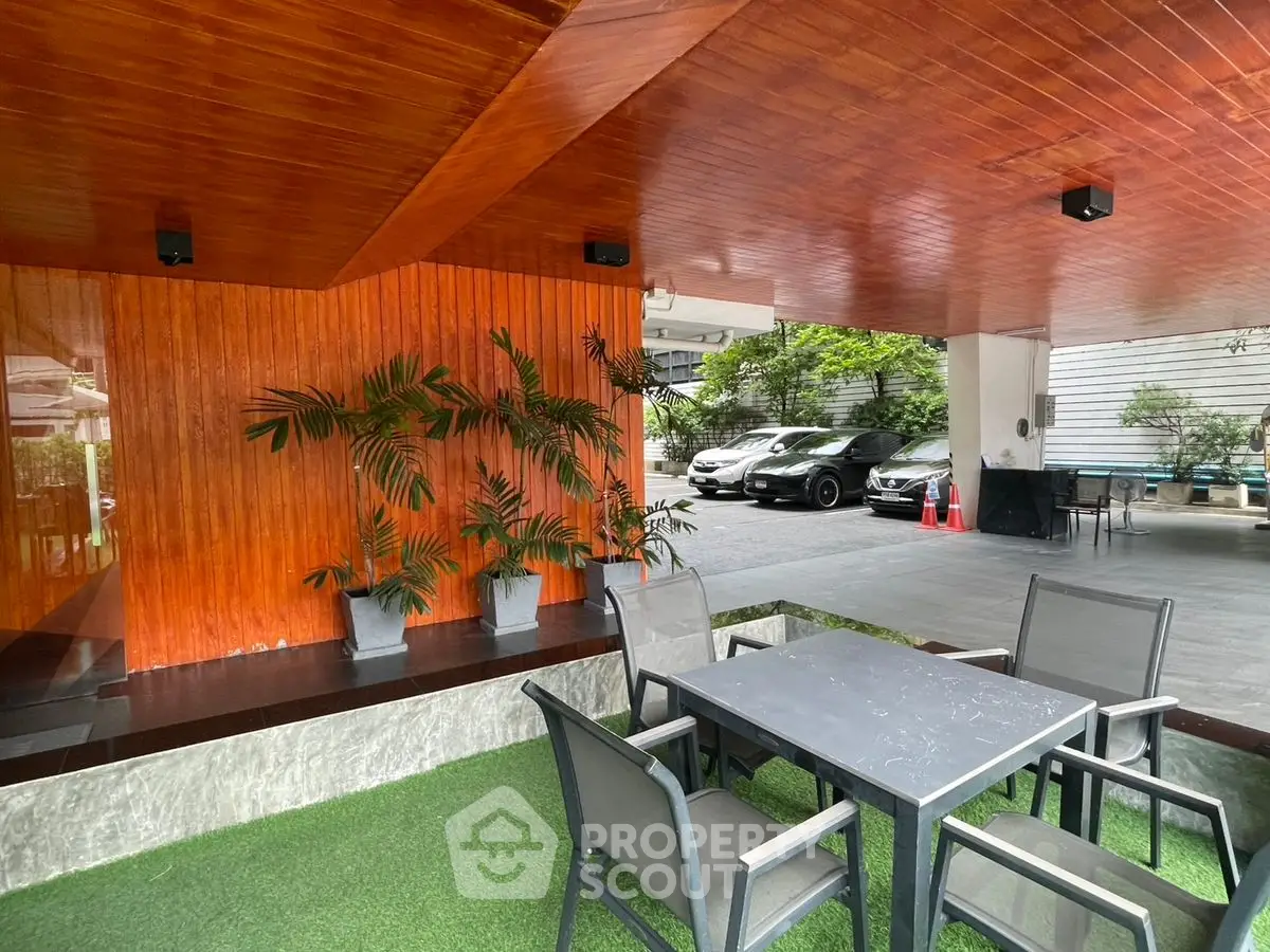 Stylish outdoor seating area in modern building with parking and greenery.