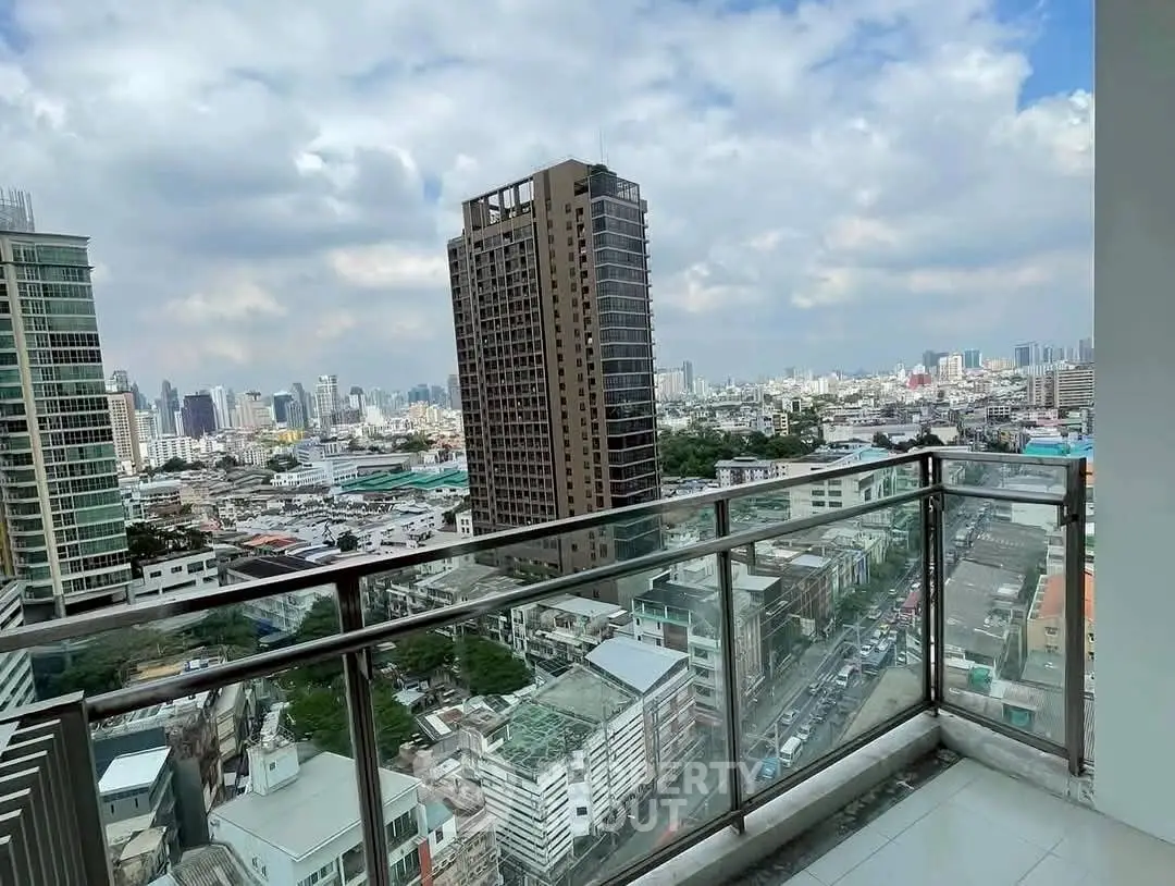 Stunning cityscape view from a modern high-rise balcony with glass railing.