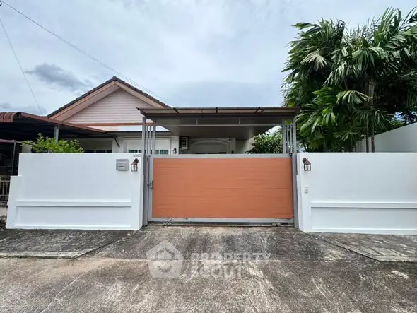 Charming single-story home with gated entrance and lush greenery, perfect for serene living.
