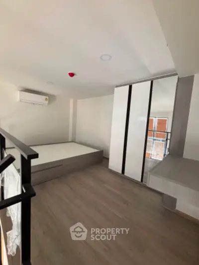 Modern bedroom with sleek design, featuring built-in wardrobe and air conditioning unit.