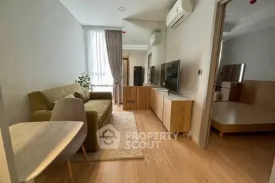Modern living room with stylish furniture and natural light, featuring a cozy sofa and sleek TV setup.