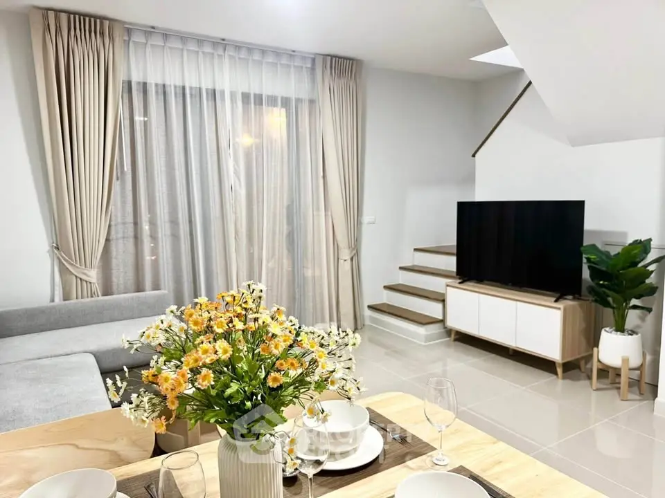 Modern living room with stylish decor, featuring a cozy sofa, elegant curtains, and a sleek TV setup.