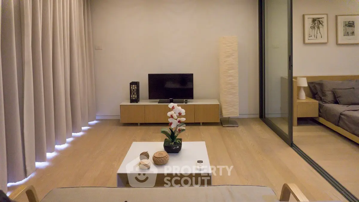 Modern living room with minimalist decor and sliding glass doors leading to a cozy bedroom.
