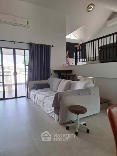 Spacious living room with modern sofa and balcony access, perfect for relaxation and entertaining.