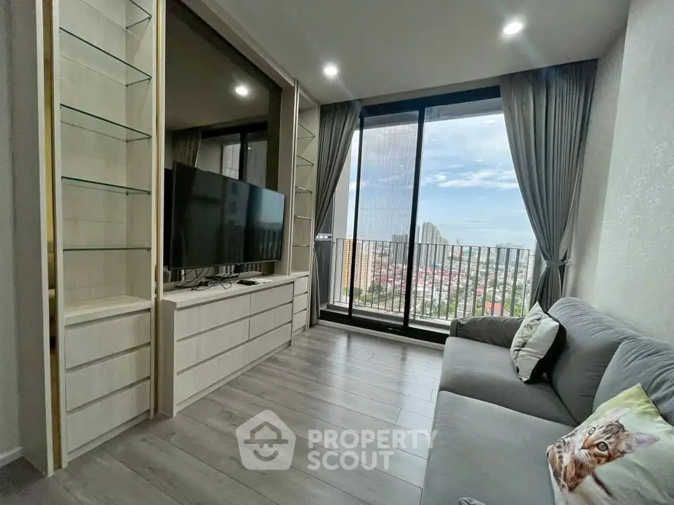 Modern living room with large window and city view, featuring sleek furniture and stylish decor.