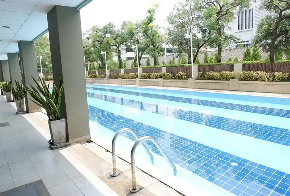 Luxurious outdoor swimming pool with sleek design and lush greenery in a modern residential complex.