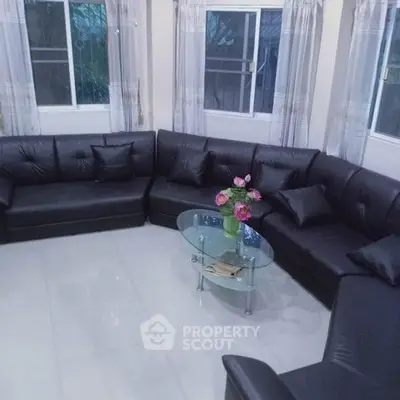 Spacious living room with modern black leather sectional sofa and glass coffee table.