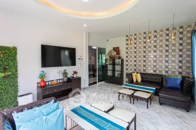 Luxurious living room with modern decor and stylish furniture, featuring a large TV and elegant wall design.