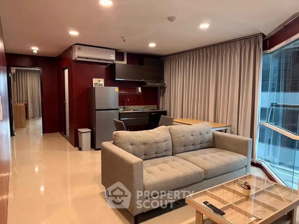 Modern living room with open kitchen, featuring a cozy sofa and dining area in a stylish apartment.