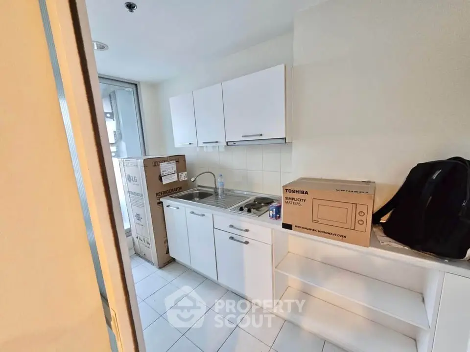 Compact kitchen with modern appliances and sleek cabinetry in a cozy apartment setting.