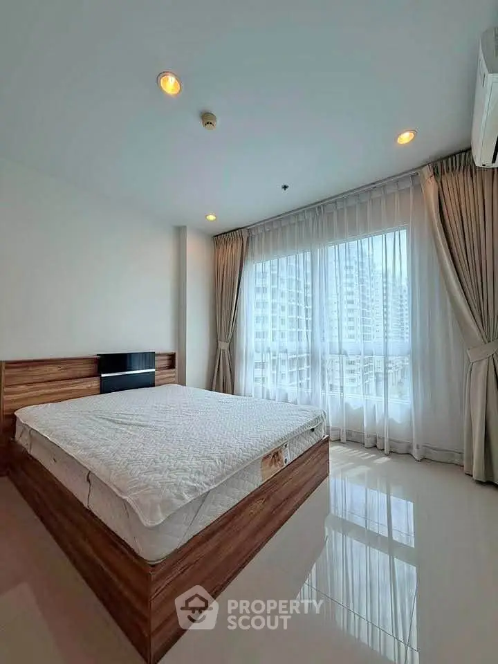 Spacious bedroom with large windows offering city views, featuring modern design and ample natural light.