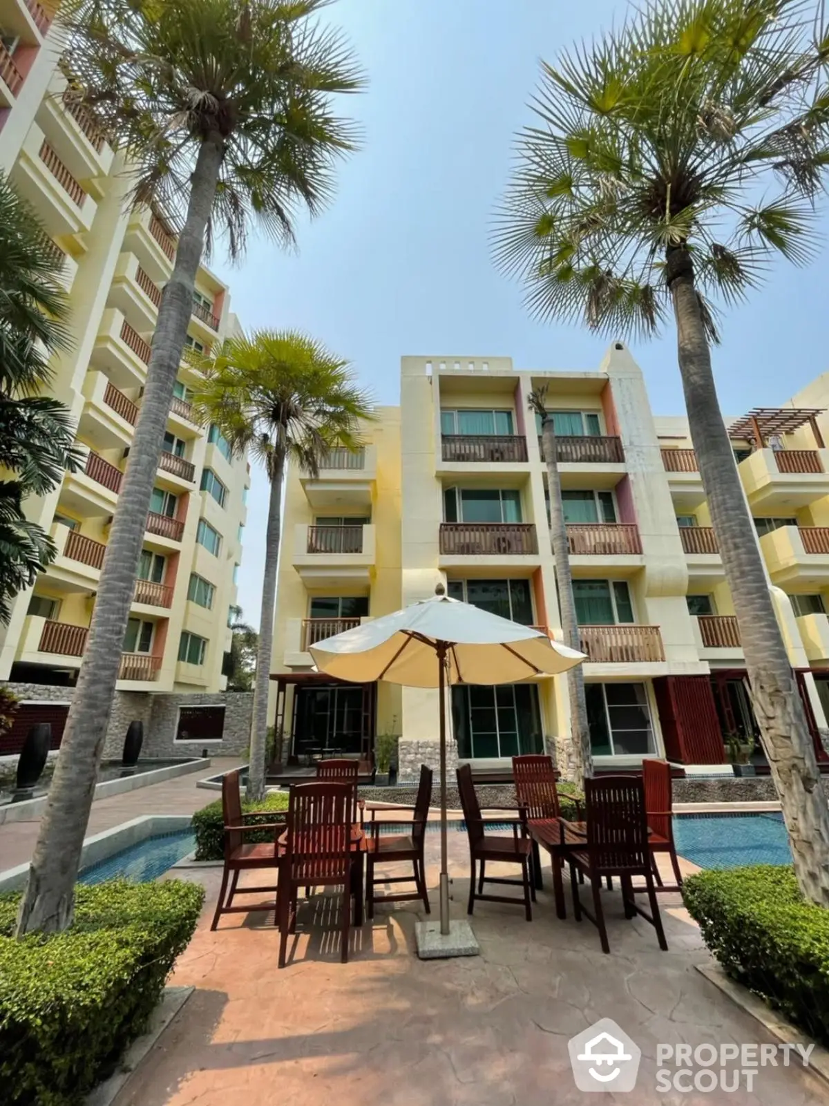 Luxurious apartment complex with poolside seating and palm trees