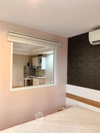 Modern bedroom with view into a compact kitchen, featuring air conditioning and stylish decor.