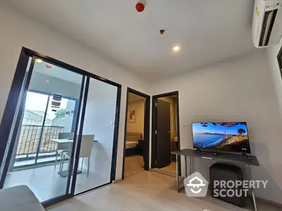 Modern living room with sleek furnishings, large flat-screen TV, and balcony access, perfect for urban living.