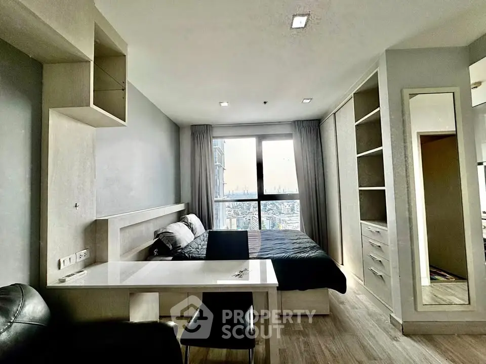 Modern bedroom with city view, featuring sleek furniture and ample storage space.