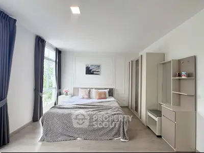 Spacious modern bedroom with large window and stylish decor