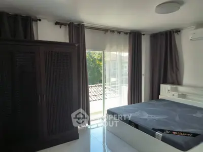 Bright bedroom with large window and modern furnishings, featuring a spacious wardrobe and comfortable bed.