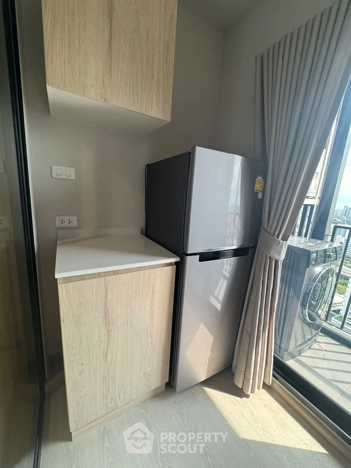 Modern kitchen corner with fridge and cabinetry in high-rise apartment