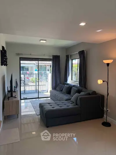 Modern living room with sleek sectional sofa and large windows for natural light.